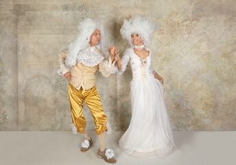 Baroque style couple in white wigs dancing in the studio