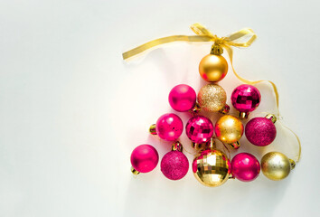 Christmas balls in the shape of a pyramid. New Year background. Pink and gold Christmas balls on a white background with a place for text.