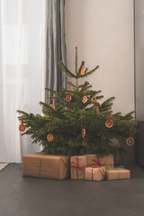 Small christmas tree with natural decorations and gift boxes