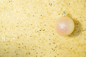 White christmas ball on gold background with sparkles with copy space