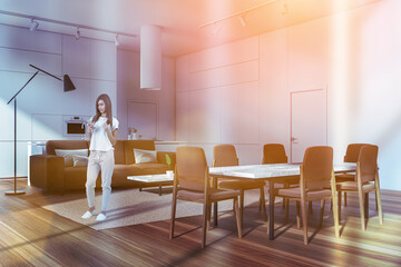 Woman in eating room interior with sofa and table with chairs