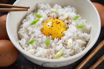 Beige bowl with tamago kake gohan or japanese warm rice mixed with a raw chicken egg, close-up, selective focus