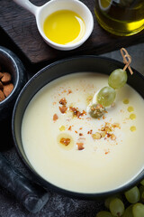 Ajoblanco or spanish white gazpacho served with grapes in a black bowl, close-up, vertical shot
