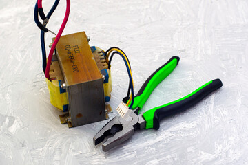 electric transformer and pliers on a gray surface
