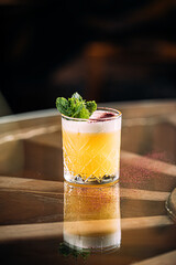 Side view on yellow whisky sour cocktail garnished with mint