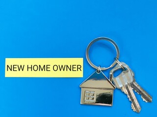Phrase new home owner written on sticky note with house keys.