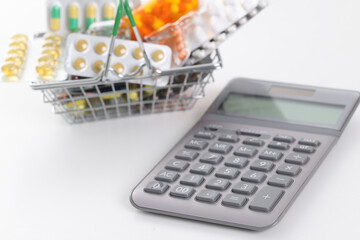 Calculator and basket with pills and capsules, close-up