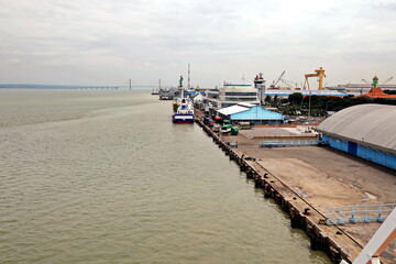 Cargo terminal for unloading steel plates from bulk carrier by ships cranes. View of the pier, cranes and various equipment. Port of Surabaya. Indonesia, January, 2021.