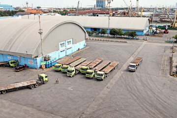 Naklejka premium Cargo terminal for unloading steel plates from bulk carrier by ships cranes. View of the pier, cranes and various equipment. Port of Surabaya. Indonesia, January, 2021.