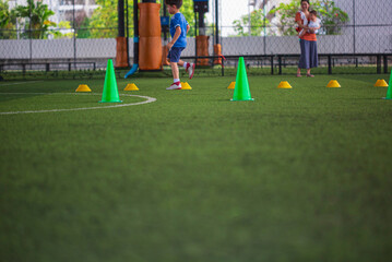 Soccer ball tactics on grass field with cone for training in background Training children