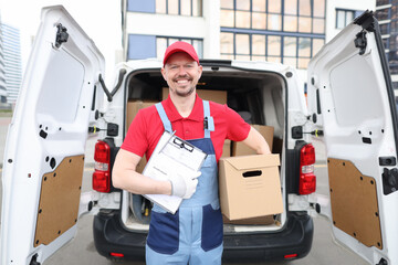 Smiling man holding a box and a delivery document