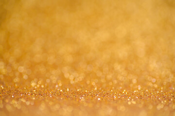 Glitter gold background. Texture foil and confetti bokeh, light of golden dust. Festive party Christmas and new year's eve background.