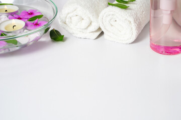 Obraz na płótnie Canvas Body care supplies, white towel, oil and rose flowers on a white background, place for text