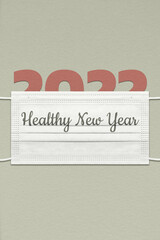 New Year's card with paper figures 2022 under a face mask with an inscription Healthy New Year.