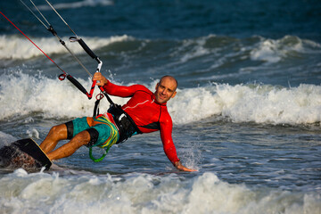 Naklejka premium Kitesurfing on the waves of the sea in Mui Ne beach, Phan Thiet, Binh Thuan, Vietnam. Kitesurfing, Kiteboarding action photos. 
