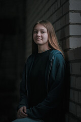 Low key portrait of a young beautiful girl in a dark room, with artistic grain and digital noise.