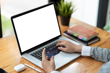 Fototapeta premium Close up of woman hands holding credit card and using laptop blank white screen. Online shopping concept.