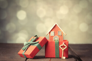 Red gift box and toy house on wooden table