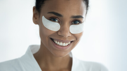 Close up head shot happy millennial african ethnicity multiracial woman with hydrogel moisturizing patches on under eyes area looking at camera, domestic self care, professional effective cosmetics.