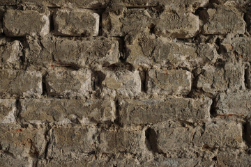 Structure of old stone damaged ancient brick wall and plaster for texture background closeup.