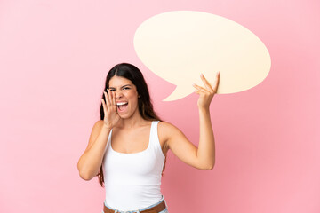 Young caucasian woman isolated on pink background holding an empty speech bubble and shouting