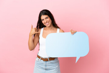 Young caucasian woman isolated on pink background holding an empty speech bubble and doing phone gesture
