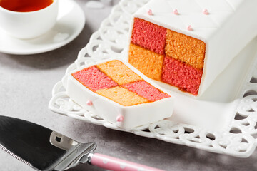 Traditional British Battenberg Cake sliced and served with cup of tea.