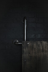 Black brick wall with installed pipe. Minimalistic background