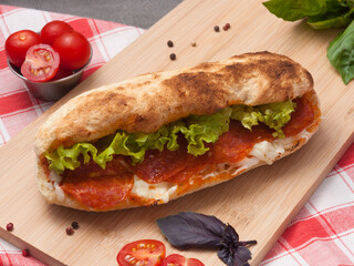pepperoni panini with cream cheese and salad on a wooden board