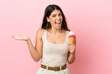 Young caucasian woman with a cornet ice cream isolated on pink background with shocked facial expression