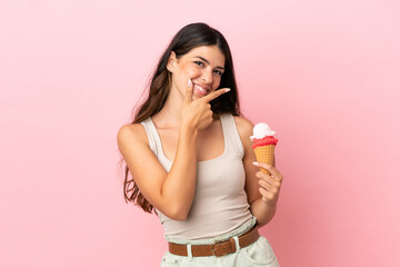 Young caucasian woman with a cornet ice cream isolated on pink background happy and smiling