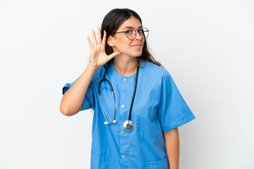 Young surgeon doctor caucasian woman isolated on white background listening to something by putting hand on the ear