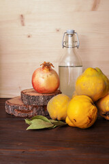 Still life with bottle, quince and pomegranate on dark wooden table. Country still life, warm color spectrum.