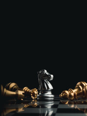 The silver horse, knight chess piece standing with falling golden queen, rook, bishop, pawn pieces on chessboard on dark, vertical. Leadership, winner, competition, and business strategy concept. © tete_escape