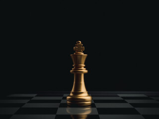 The golden king chess piece standing alone on chessboard on dark background. Leader, influencer, lonely, commander, strong, and business strategy concept.