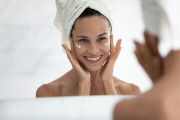 Mirror reflection happy beautiful millennial mixed race woman with wrapped in towel wet hair...
