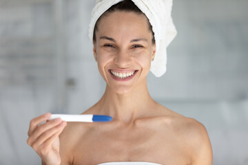 Portrait of sincere joyful young latina hispanic woman holding plastic stick test in hands, feeling excited of pregnancy confirmation results, fertility maternity, childbirth planning concept.