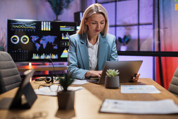 Beautiful caucasian woman in formal clothes sitting at desk and typing on wireless laptop. Female person with blond hair working at office on portable computer.