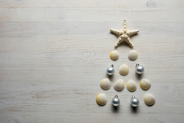 Christmas tree from sea shells and starfish on blue background, top view
