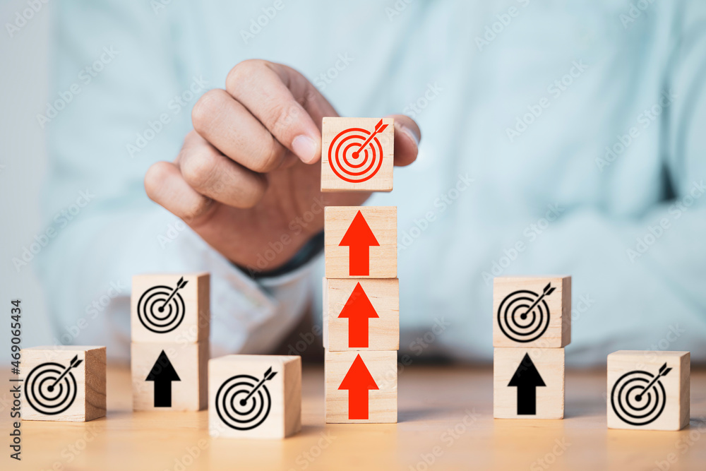Poster businessman putting target board on up arrows which print screen on wooden cube block, increasing an