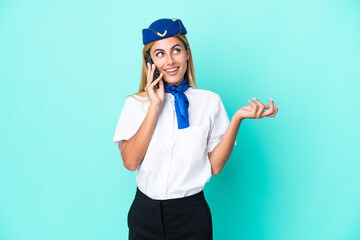 Airplane stewardess Uruguayan woman isolated on blue background keeping a conversation with the mobile phone with someone
