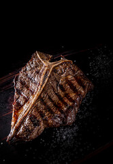 Grilled T-bone Steak on bones on wooden board on dark background
