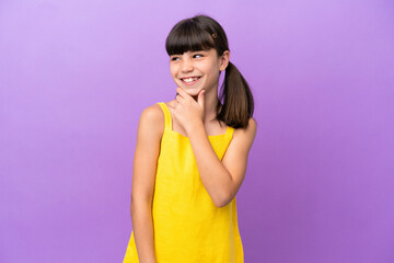 Little caucasian kid isolated on purple background looking to the side and smiling