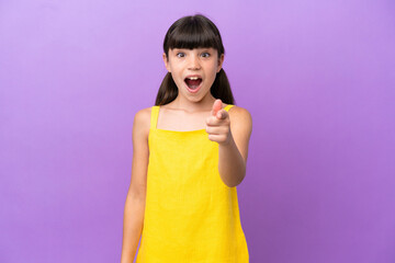 Little caucasian kid isolated on purple background surprised and pointing front