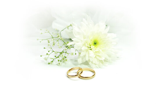 Wedding rings and white flower on white tulle background