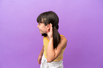 Little caucasian kid isolated on purple background listening to something by putting hand on the ear