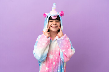 Little kid wearing a unicorn pajama isolated on purple background smiling with a happy and pleasant expression