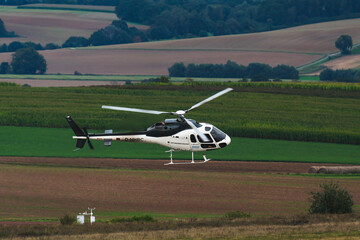 Helicopter in flight with fields and a forest in the background
