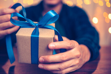 Hands holding gift box, present on the table and light of bokeh background. Valentine's Day,...
