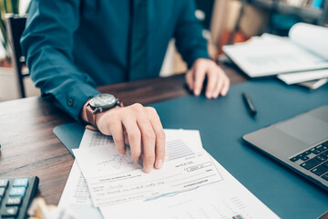 A Businessperson's hand giving cheque to customer and dollar bill, coin, laptop and graph chart on...
